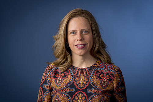 Vrouw met bruin haar, blank en gekleurde blouse aan op een blauwe achtergrond