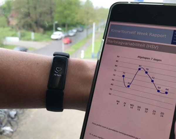 Persoon draagt een fitbit en ziet op de telefoon de uitslag van de hartslagvariabiliteit