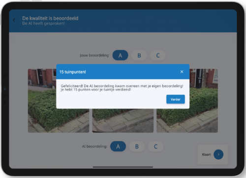 iPad waarop Groen-app is geopend. Pop-up melding te zien met tekst Gefeliciteerd! De AI kwam overeen met je eigen beoordeling! Je hebt 15 punten voor je tuintje verdiend!