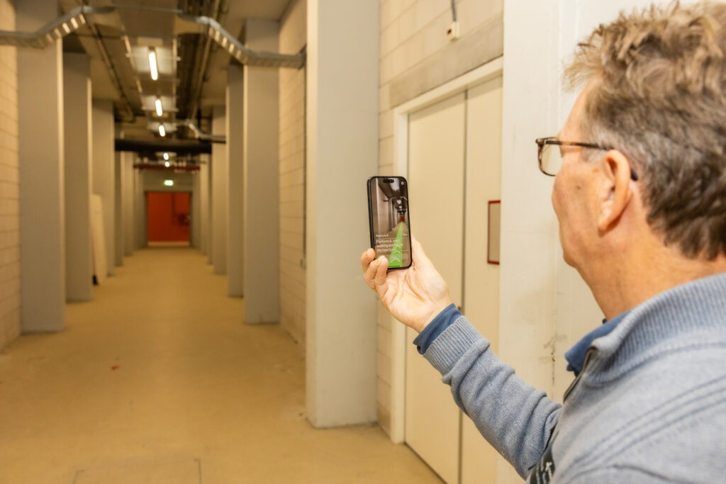 Een gebruiker van naext ziet op zijn telefoon een groene lijn met pijlen door een hal lopen die de route aangeeft